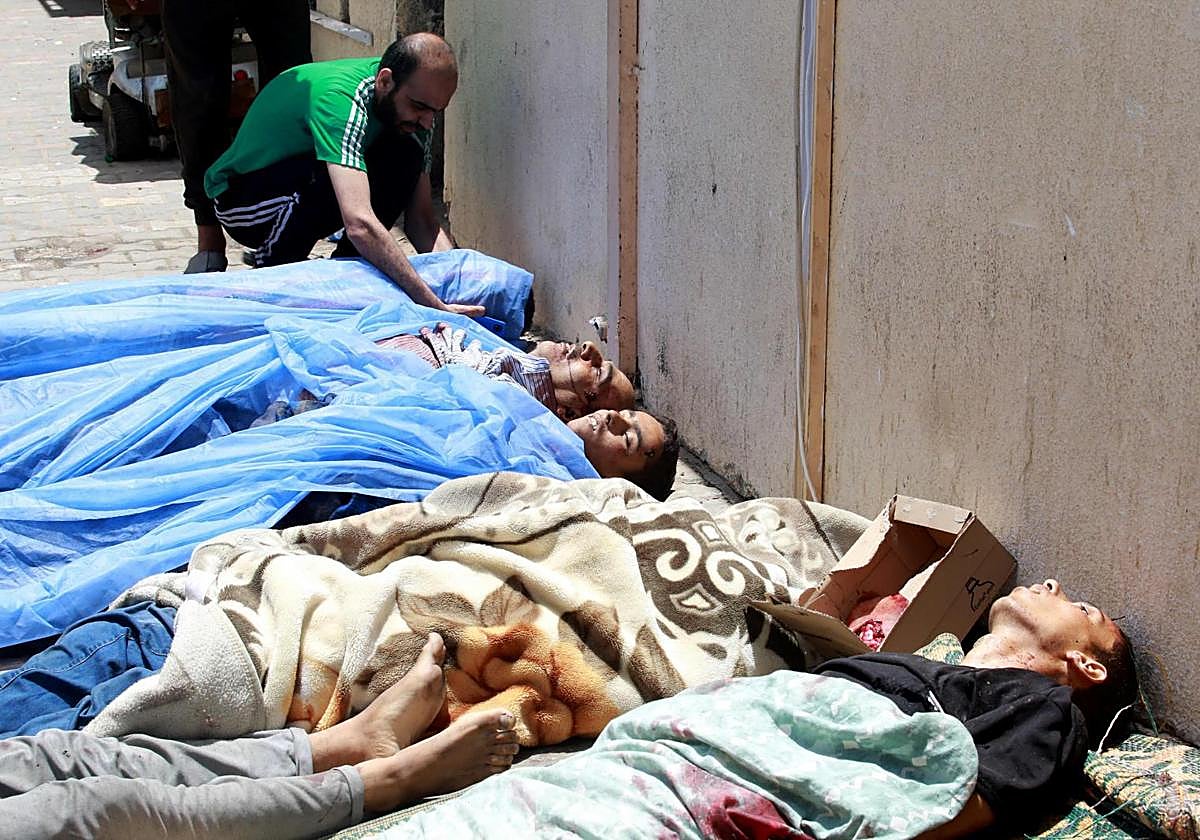 Los cuerpos de las víctimas tumbados y cubiertos tras el bombardeo israelí de un apartamento residencial en Deir al-Balah y de al-Maghazi