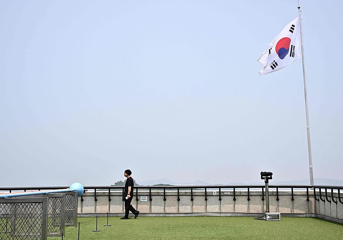 Un hombre camina bajo la bandera nacional de Corea del Sur en un mirador desde donde los visitantes pueden mirar hacia Corea del Norte