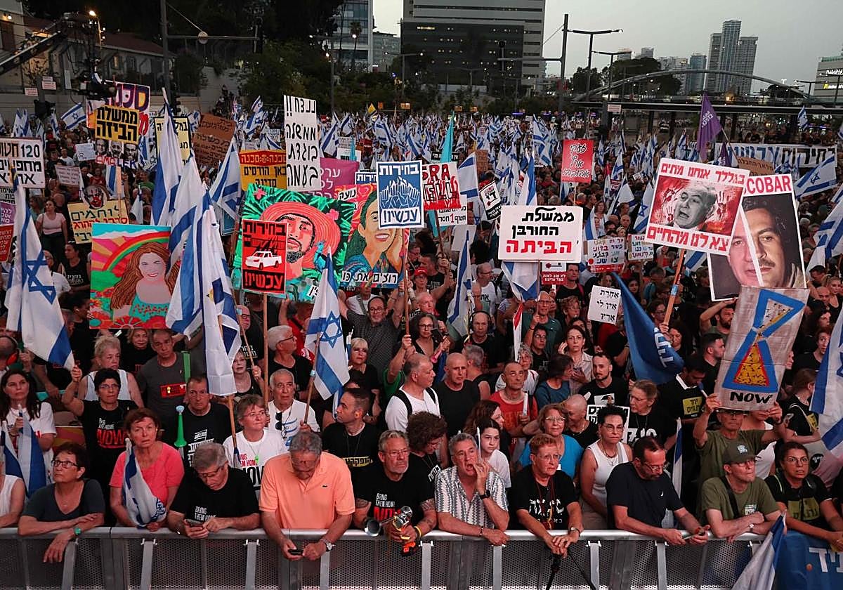Manifestantes israelíes levantan banderas y pancartas durante una manifestación antigubernamental en Tel Aviv