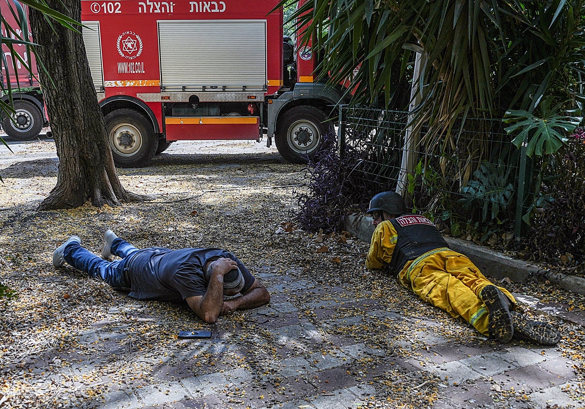 En vídeo: El jefe de Hizbolá dice que tiene ofertas de refuerzo exterior | Foto: Dos hombres cuerpo a tierra tras sonar la alarma por los cohetes entrantes desde el Líbano hacia Israel