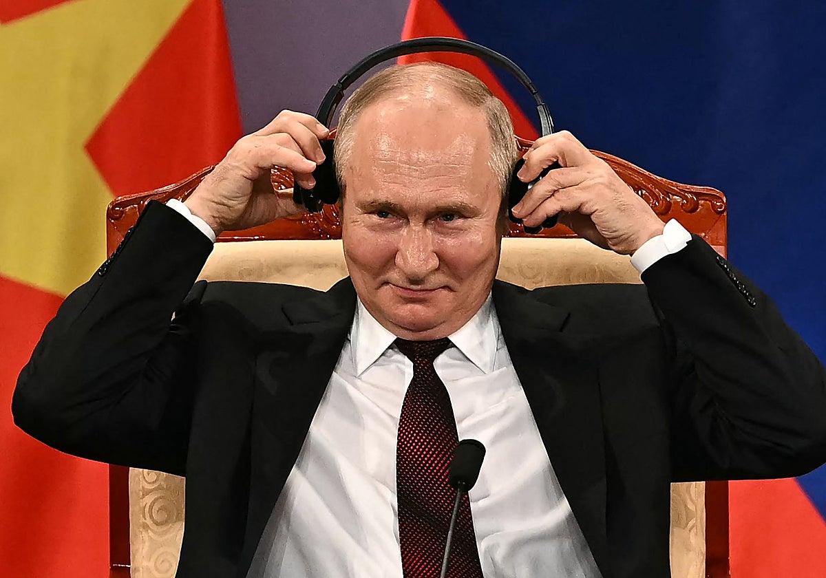 Putin se ajusta unos auriculares durante un evento con el presidente de Vietnam To Lam