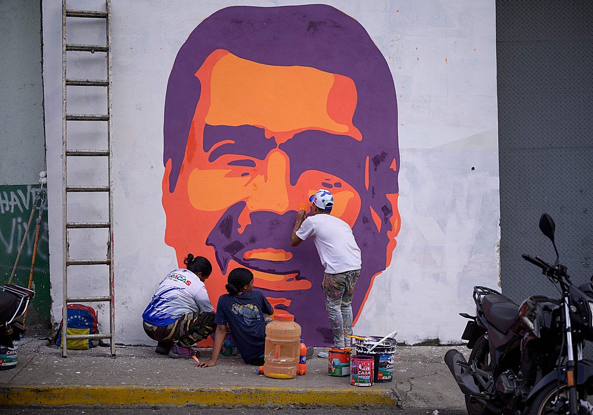 Varias personas pintan un mural del presidente venezolano Nicolás Maduro durante una concentración en Caracas