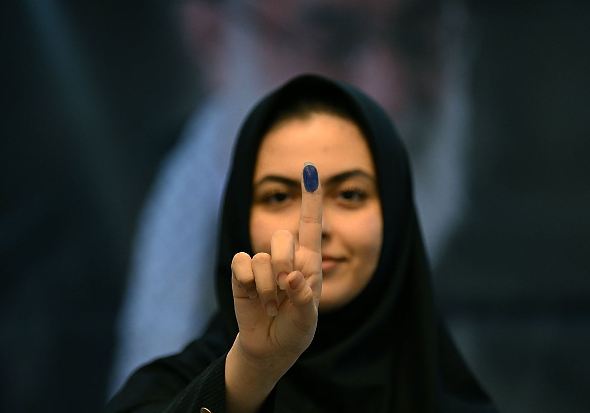 Una mujer iraní muestra su dedo con tinta tras votar en la Embajada de Irán en Kuwait