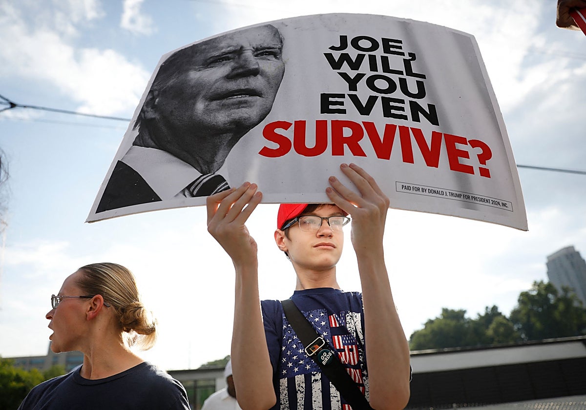 Un joven sostiene un cartel donde se pregunta si el presidente Biden sobrevivirá