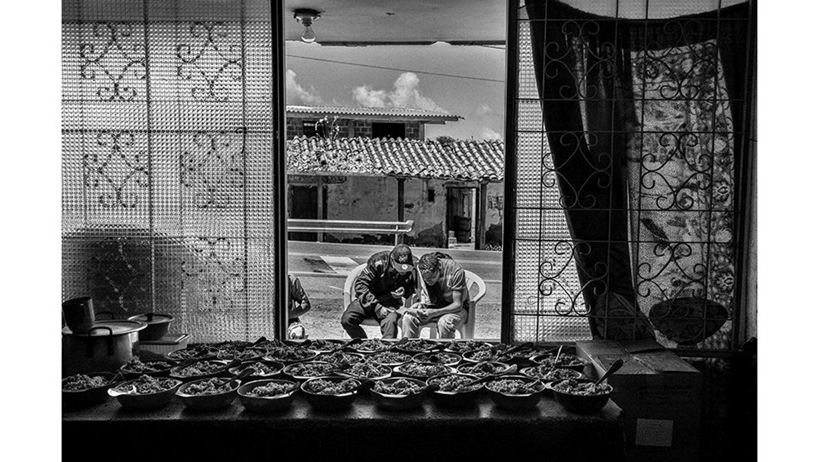 Cúcuta (norte de Santander, Colombia), 13 de febrero de 2019. Dos emigrantes venezolanos observan una nota informativa mientras esperan su turno para comer en el albergue de Paso del Candelero, cerca del páramo de Berlín. La crisis humanitaria en Venezuela ha obligado a millones a huir en busca de mejores condiciones de vida. Cúcuta, en la frontera con Venezuela, es un punto crucial para estos migrantes, que enfrentan numerosos desafíos en su travesía.
