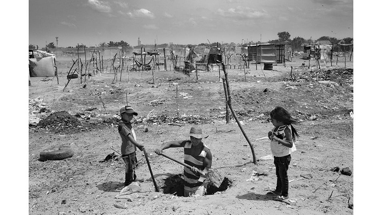 Maicao (Colombia), 17 de abril de 2021. José Luis Rincón y dos de sus hijos trabajan arduamente para construir una fosa séptica en el terreno que ocupan en el asentamiento conocido como La Pista. Este lugar, uno de los mayores asentamientos ilegales de migrantes venezolanos en Colombia, alberga a más de 7,000 familias con un promedio de 5 miembros por hogar