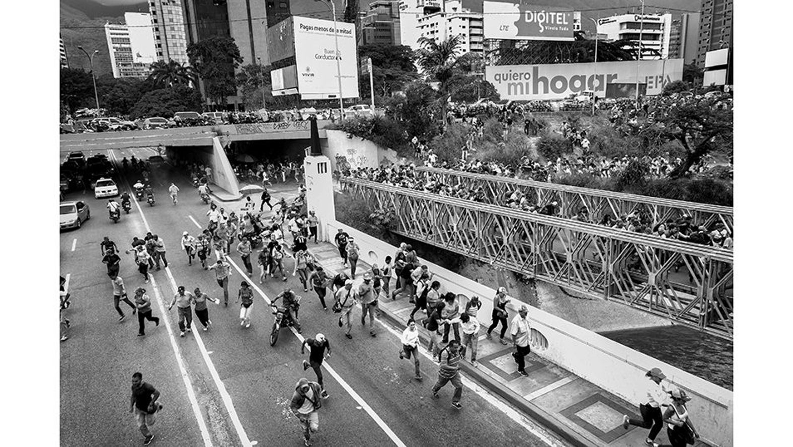 Caracas (Venezuela), junio de 2016. Manifestantes opositores al gobierno revolucionario de Nicolás Maduro huyen de la policía durante una marcha que terminó en violencia. Las manifestaciones de la oposición venezolana, exigiendo un referéndum revocatorio y un cambio de gobierno, eran constantes en todo el país. En 2016, la crisis política y económica en Venezuela alcanzó niveles críticos, con hiperinflación y escasez de alimentos y medicinas