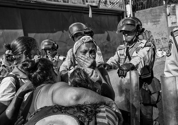 Imagen secundaria 1 - Caracas, 27 de mayo de 2016. Un grupo de presos encerrados en sus celdas dentro de la comisaría municipal de Chacao, ubicada al este de Caracas (foto superior). Debajo: una mujer er llora frente a la policía el 5 de junio de 2016 por la angustia de no tener noticias de su hermano, uno de los 600 detenidos que se han amotinado dentro de la Comisaría de la Policía Nacional en la zona 7 de Los Ruices. El cadáver de un joven víctima de un asesinato espera a ser enterrado en el interior de una morgue de un hospital de Caracas el 29 de julio de 2015 