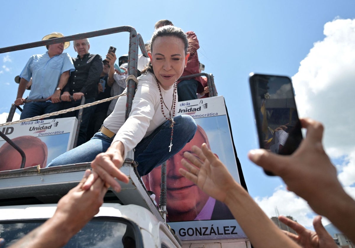 La líder opositora venezolana María Corina Machado se estira para saludar a sus partidarios durante una protesta convocada por la oposición