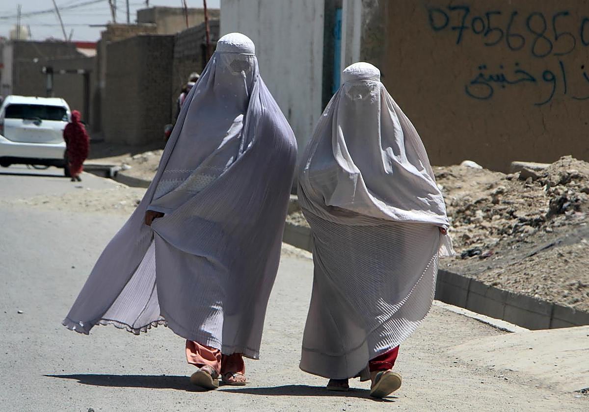 Mujeres afganas vestidas con el burka caminan por una carretera en Kandahar, Afganistán