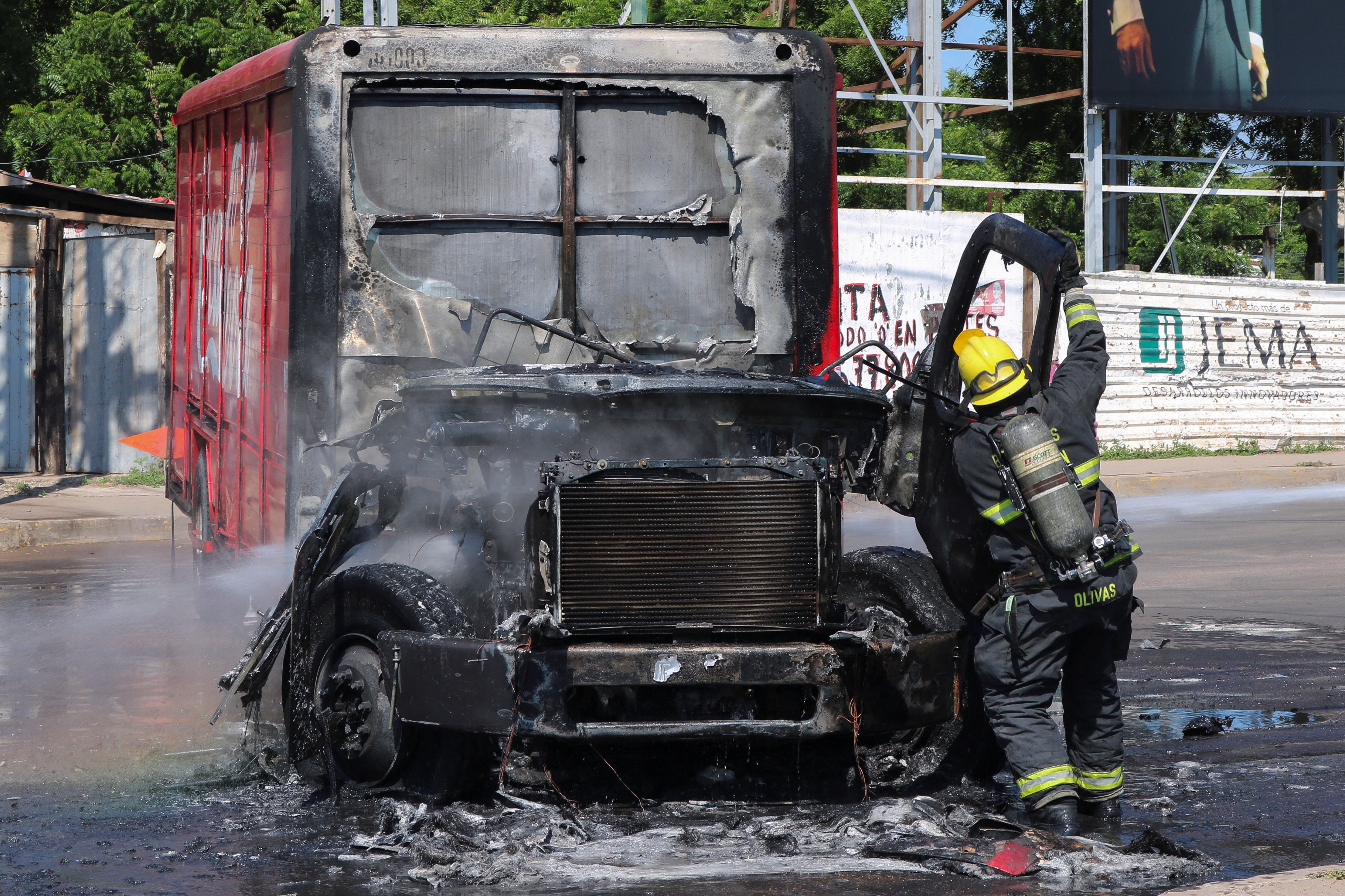 Un bombero acude al lugar en el que ha sido quemado un camión de repartoen medio de una ola de violencia entre grupos armados.