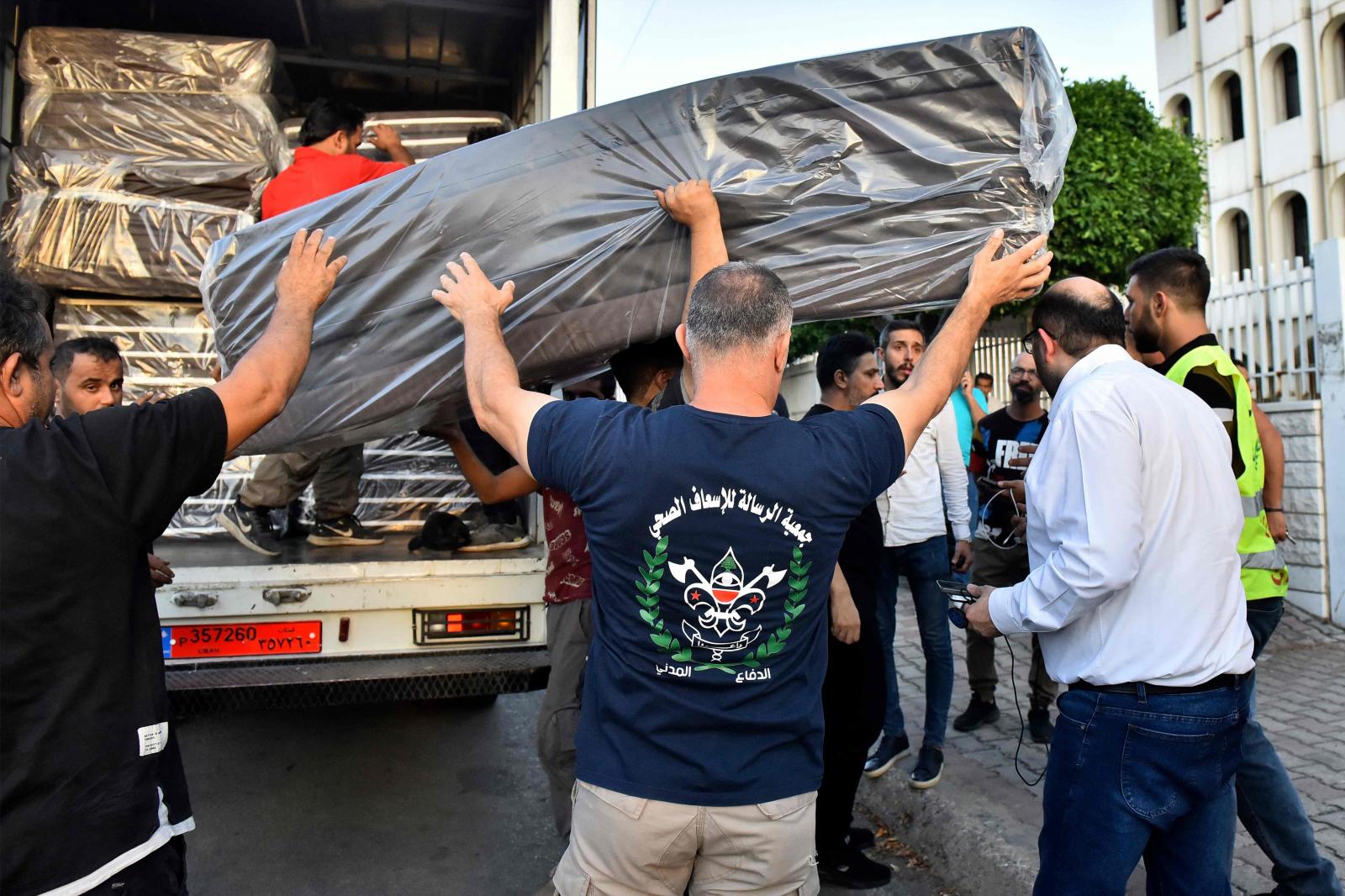 Numerosos voluntarios descargando colchones de un camión