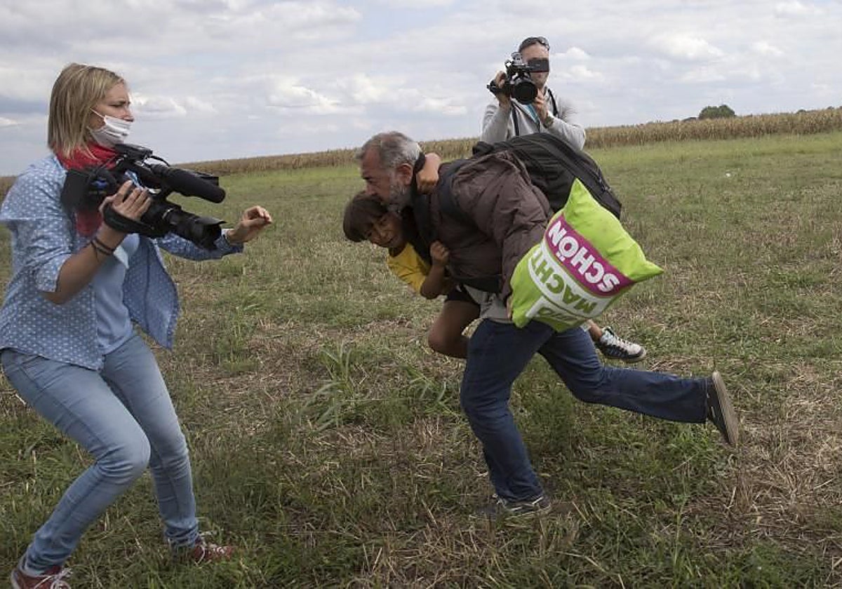 Un migrante corre con un niño  mientras intenta escapar de un punto de recogida en el pueblo de Roszke, Hungría
