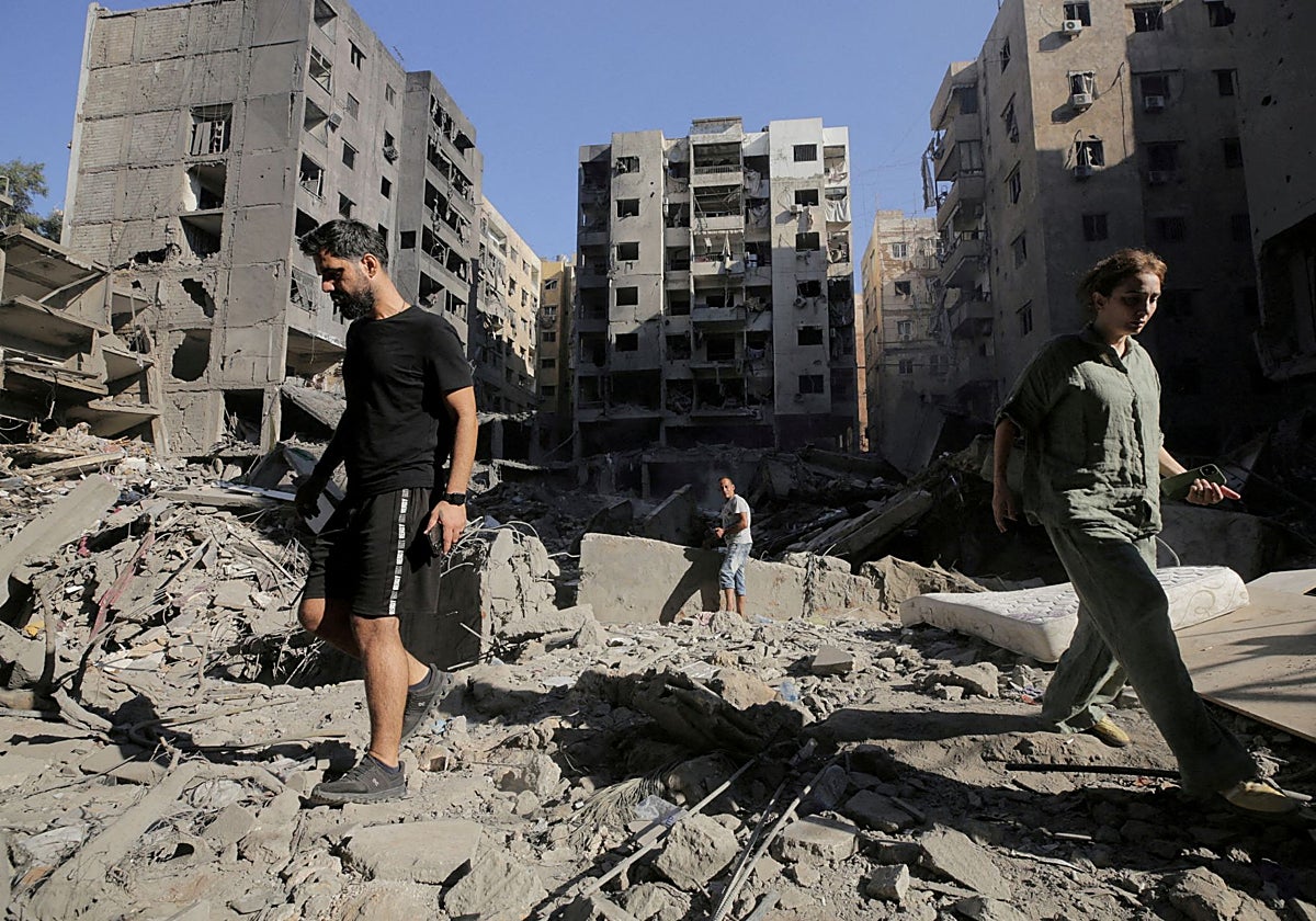 La gente camina sobre los escombros en el lugar del ataque aéreo israelí