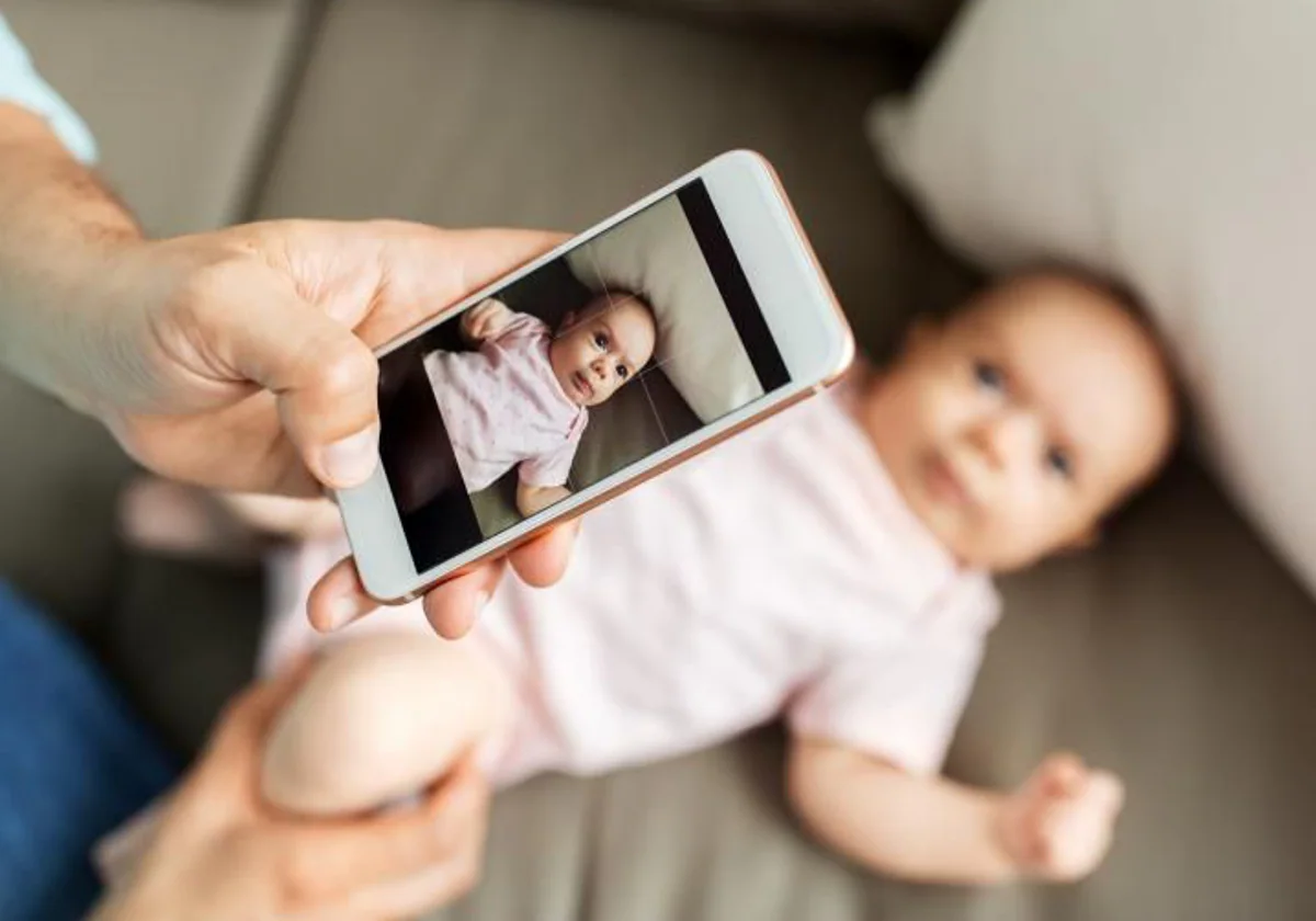 Un padre, sacando una foto de su bebé en una imagen de archivo