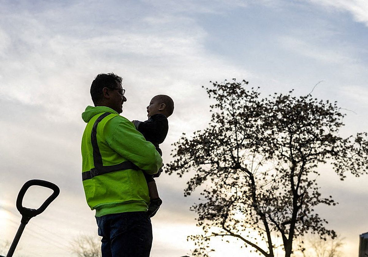 Ronal Pinto, de Venezuela , sostiene a su hijo después de regresar a casa de un día de trabajo en un sitio de construcción en Columbus, Ohio