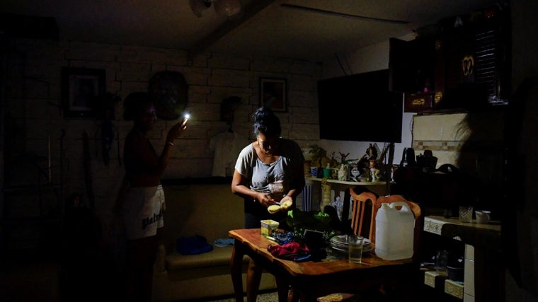 Una mujer prepara comida con la ayuda de la luz de un móvil mientras Cuba está sumida en la oscuridad