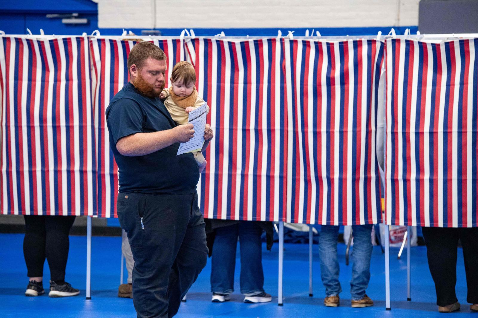 Un votante junto a su bebé con una papeleta rellenada después de votar en el Centro Comunitario de Green Street en Concord, Nuevo Hampshire