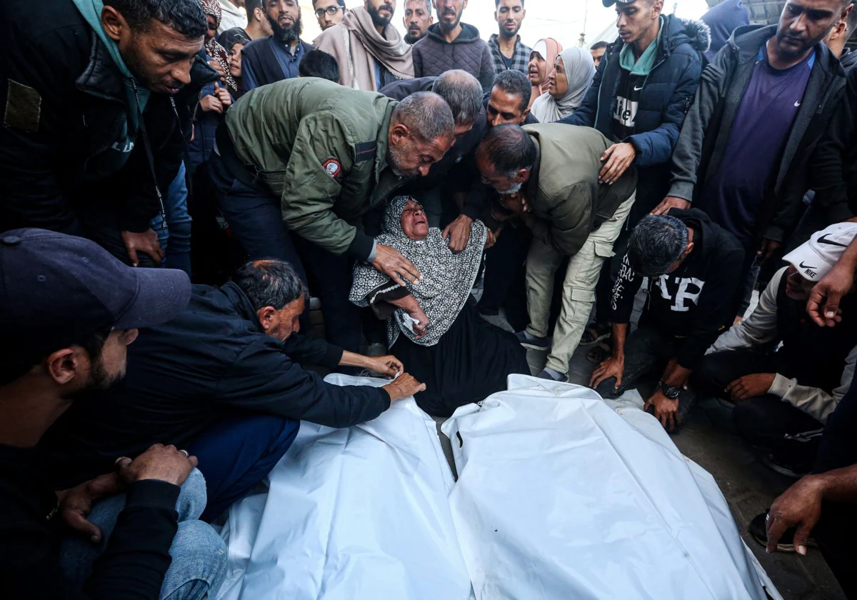 Familiares de palestinos muertos en un ataque israelí contra las tiendas de campaña de desplazados lloran mientras reciben sus cuerpos en el Hospital de los Mártires de Al Aqsa