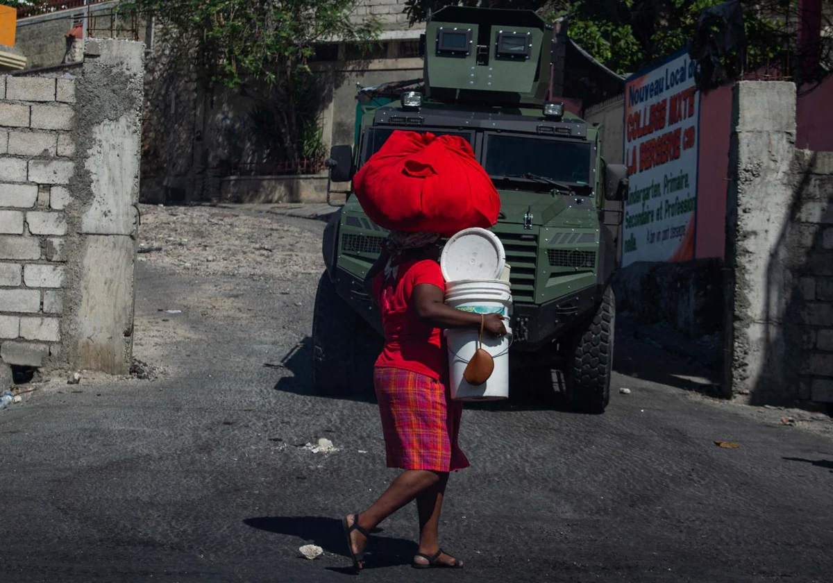 Una mujer carga con sus pertenencias mientras abandona el barrio de Solino en Puerto Príncipe