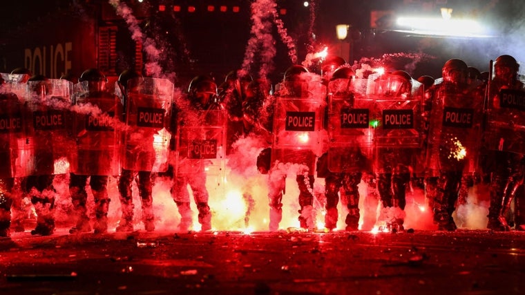 Los fuegos artificiales lanzados por los manifestantes explotan a lo largo de las líneas policiales, afuera del Parlamento de Georgia en Tiflis