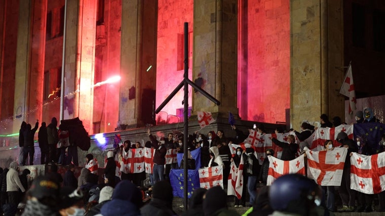 Manifestantes sostienen banderas nacionales de Georgia durante una protesta frente al edificio del Parlamento