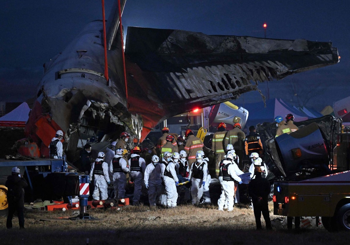 Personal de rescate surcoreano lleva el cuerpo de una víctima tras el accidente del Boeing 737-800 de Jeju Air