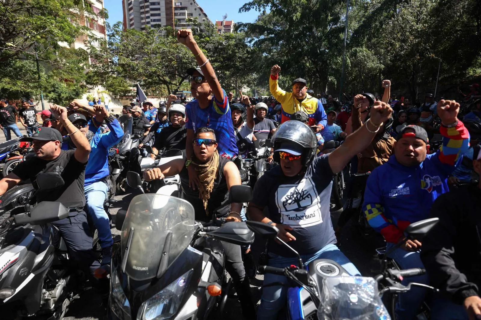 Partidarios de Maduro en motocicletas hacen un gesto mientras pasan junto a una protesta convocada por la oposición en vísperas de la investidura presidencial, en Caracas