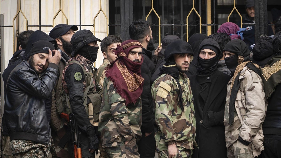 Varios hombres esperan para alistarse a las Fuerzas Armadas sirias en un centro de reclutamiento de Idlib