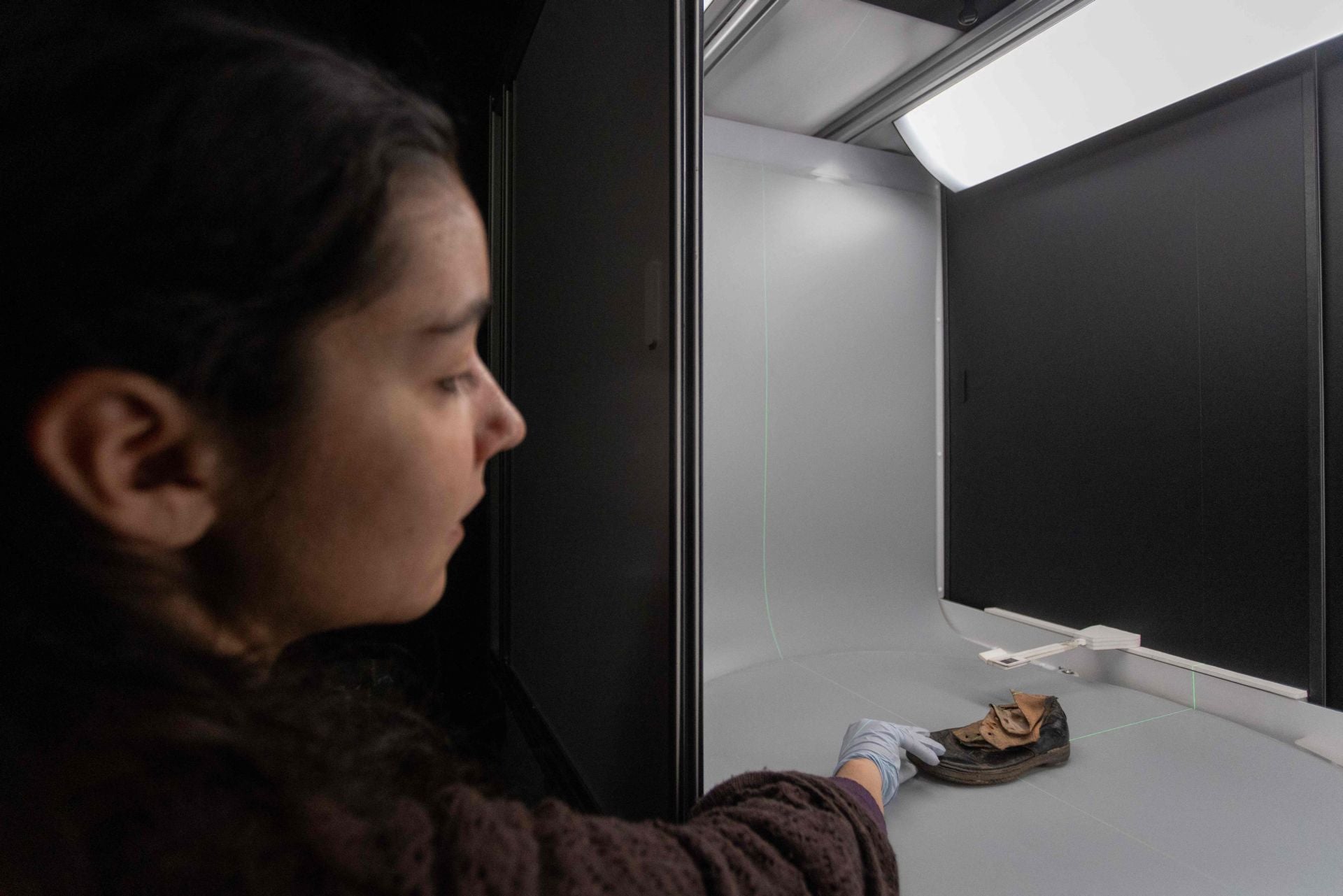 Una voluntaria del laboratorio de conservación documenta un zapato infantil