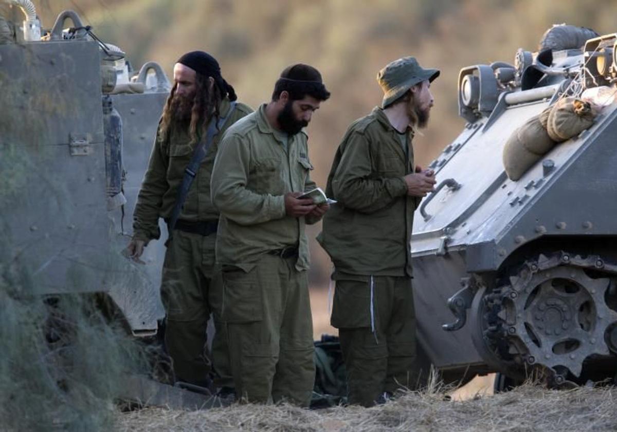 Un grupo de reservistas israelíes rezan junto a un tanque