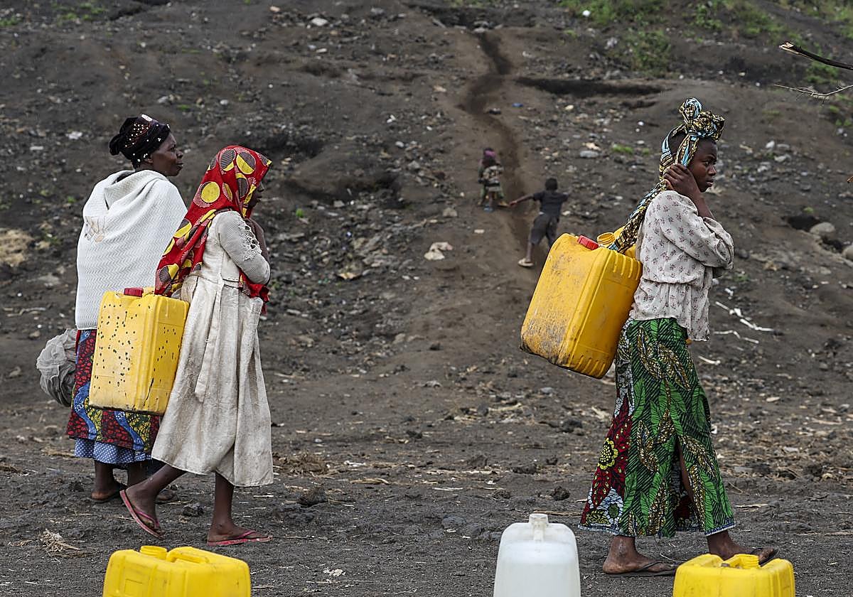 Un grupo de mujeres desplazadas van a recoger agua con bidones.