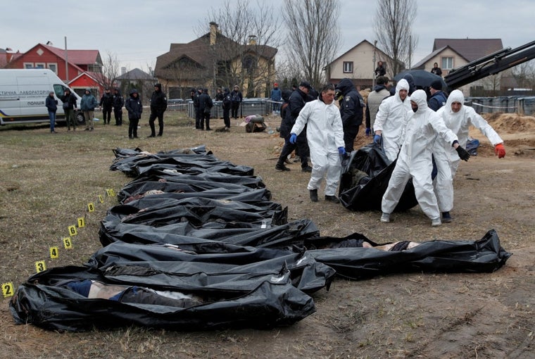 Técnicos forenses exhuman los cadáveres que fueron sepultados en una fosa común después de la masacre rusa en las afueras de Kiev, en 2022