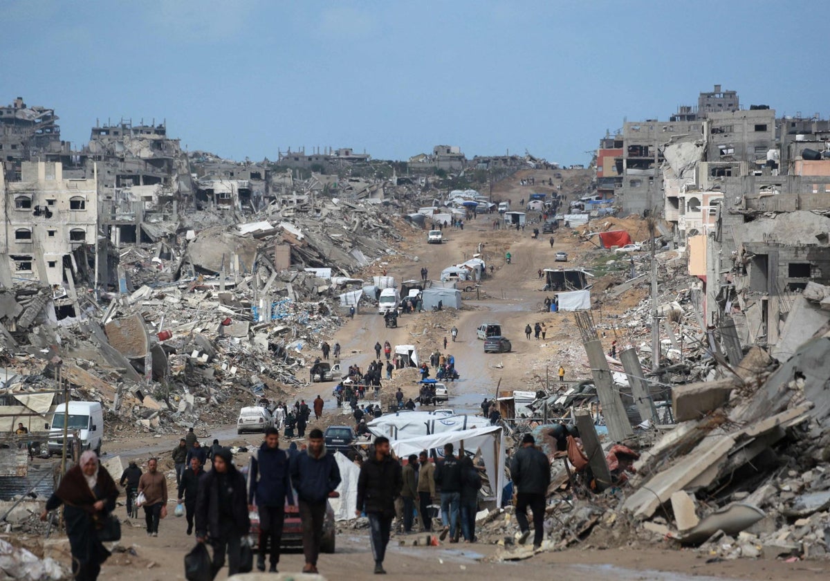 Palestinos desplazados caminan por un camino embarrado en medio de la destrucción en Jabalia, en el norte de la Franja de Gaza