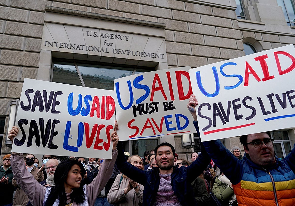 La gente sostiene carteles mientras el edificio de USAID permanece cerrado