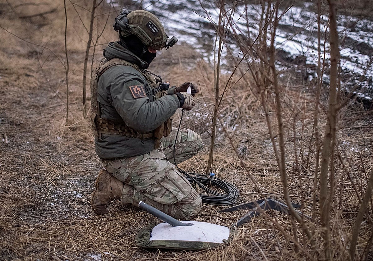 Un militar ucraniano  prepara un sistema de internet satelital Starlink en sus posiciones en la línea del frente
