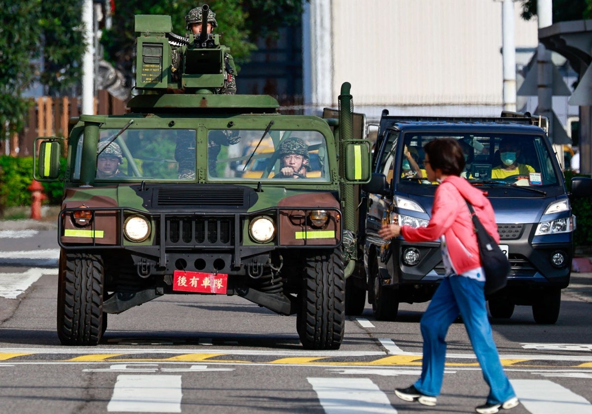 Un peatón cruza la calle frente a un vehículo militar armado que patrullaba las afueras del Aeropuerto Songshan en Taipéi el 14 de octubre de 2024.