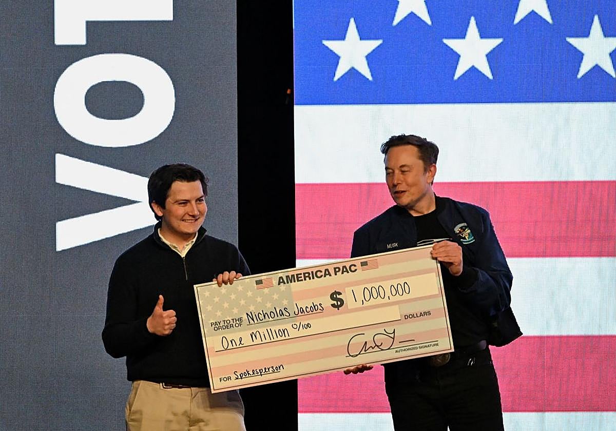 El asesor del presidente Donald Trump, Elon Musk, entrega un cheque a un miembro del público en un mitin de apoyo a un candidato conservador a la Corte Suprema estatal de Wisconsin