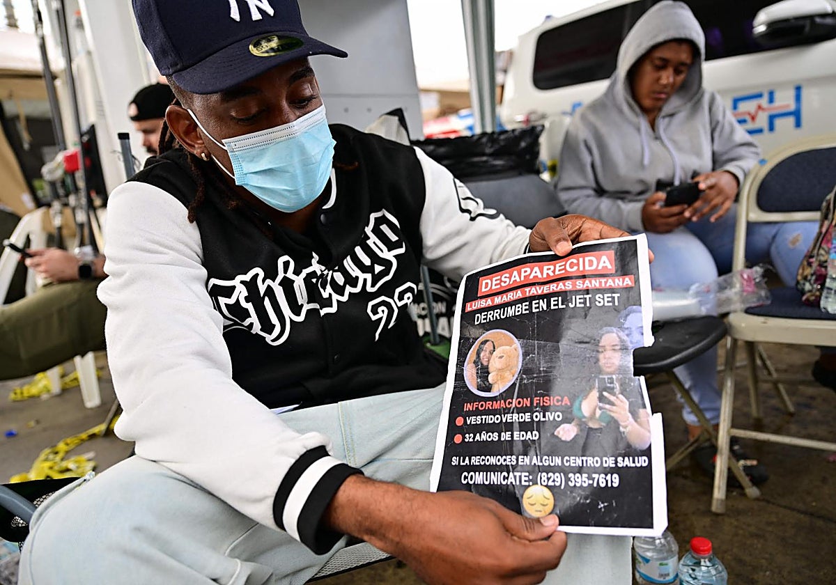 Un hombre muestra la fotografía de una de las personas que asistieron al concierto del lunes en la discotea Jet Set y que sigue desaparecida