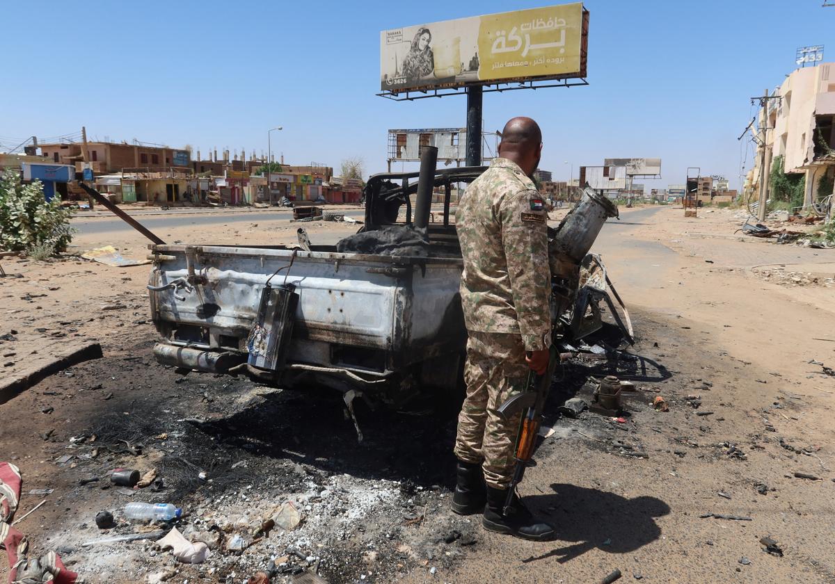Un soldado del ejército sudanés junto a un vehículo de combate destruido en el estado de Jartum