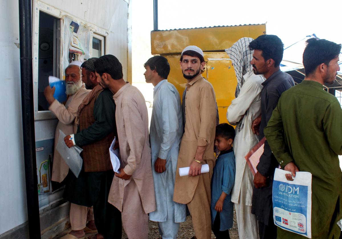 Afganos, expulsados de Pakistán, hacen cola para registrarse a su llegada al campo de refugiados de Omari