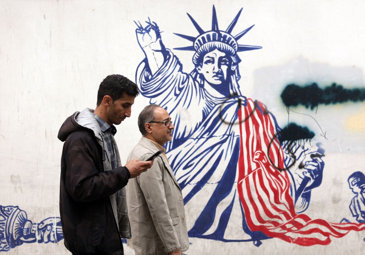Varias personas caminan cerca de un mural contra Estados Unidos junto a la antigua embajada estadounidense en Teherán, Irán