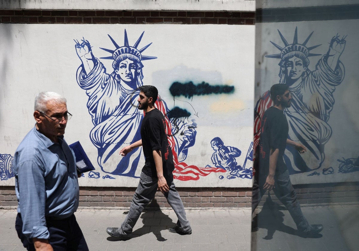La gente pasa junto a un mural antiestadounidense en una calle de Teherán
