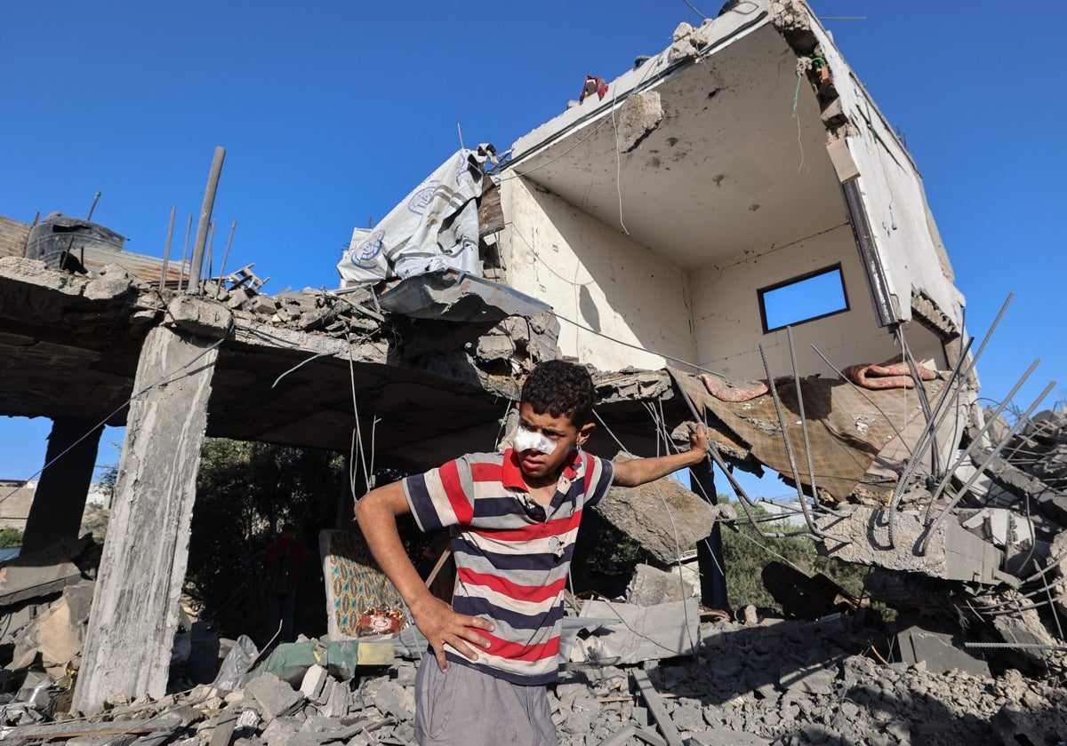 Un niño palestino se encuentra frente a una casa destruida que fue blanco de un ataque israelí en el campamento de refugiados de Nuseirat, en el centro de la Franja de Gaza ,