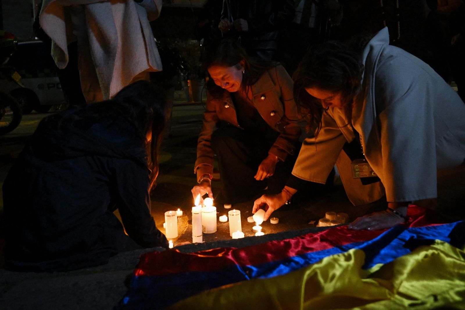 Un grupo de mujeres enciende velas frente a la Clínica Fundación Santa Fe, donde el senador Miguel Uribe recibe tratamiento médico tras ser herido de bala en Bogotá.