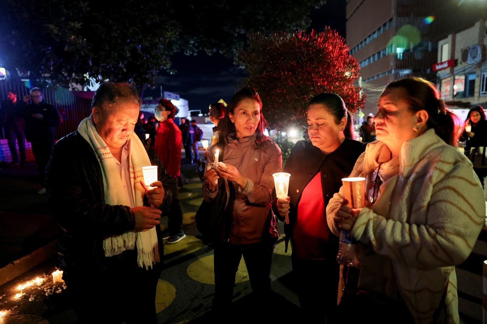 Varias personas sostienen velas y rezan frente al hospital de la Fundación Santa Fe.