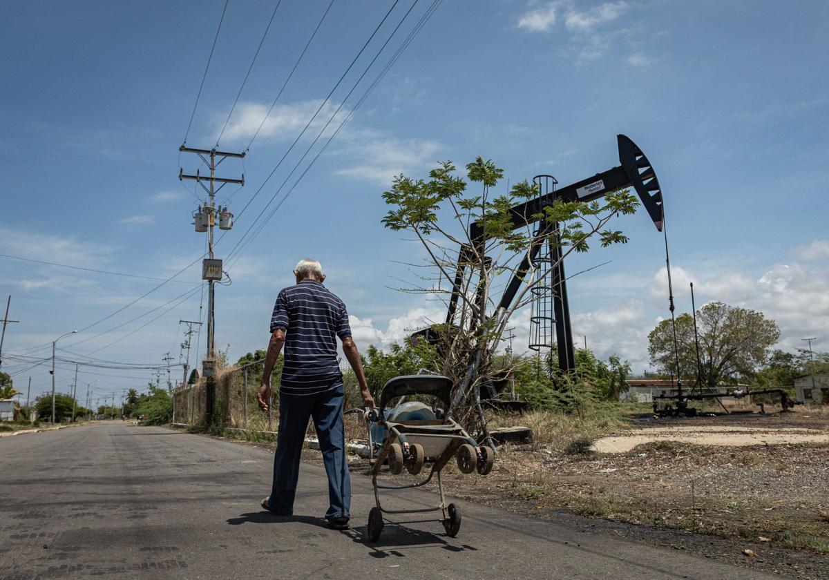 Un hombre camina junto a una unidad de bombeo de petróleo este martes, en Maracaibo