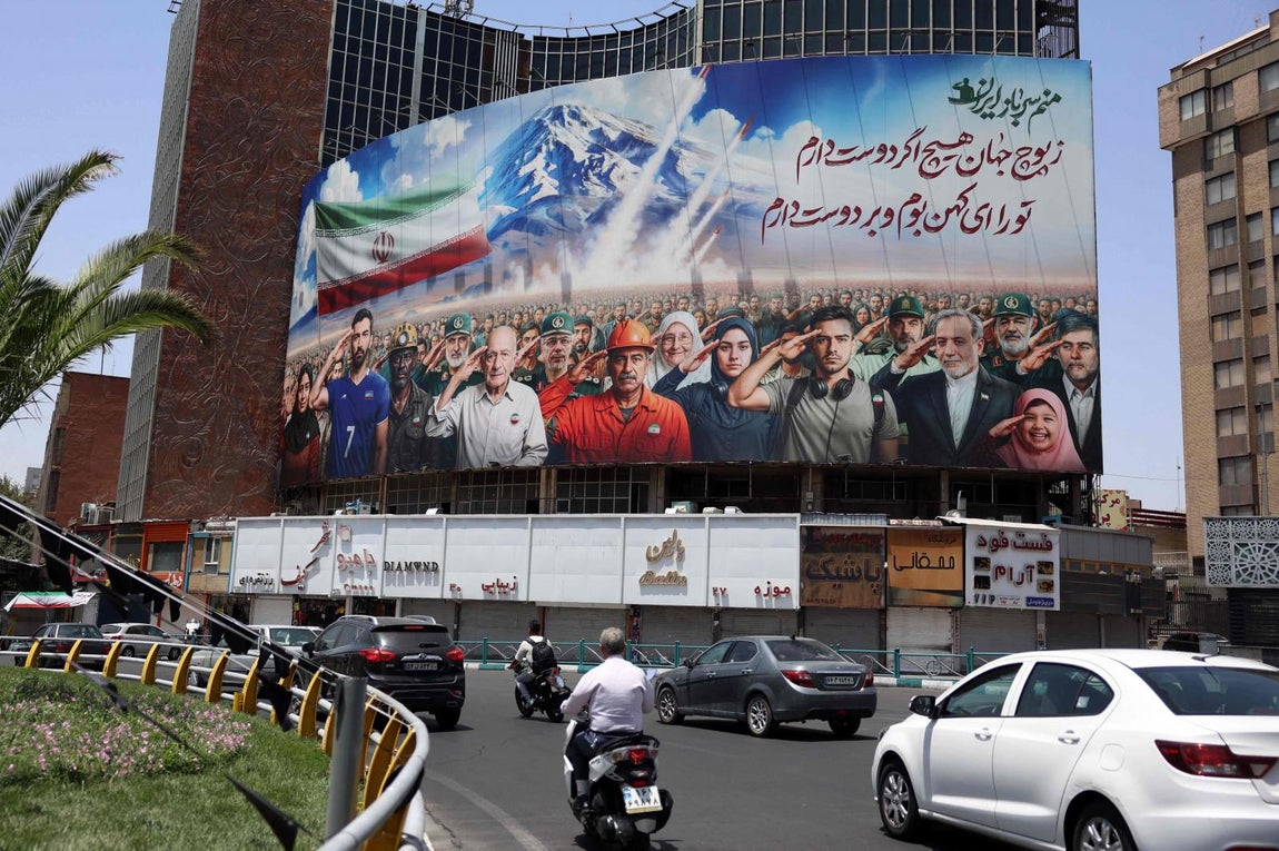 Una pancarta con una pintura que representa diversas categorías de la sociedad iraní se despliega contra la fachada de un edificio en Teherán, con un mensaje que dice en farsi: "Todos somos soldados de Irán"