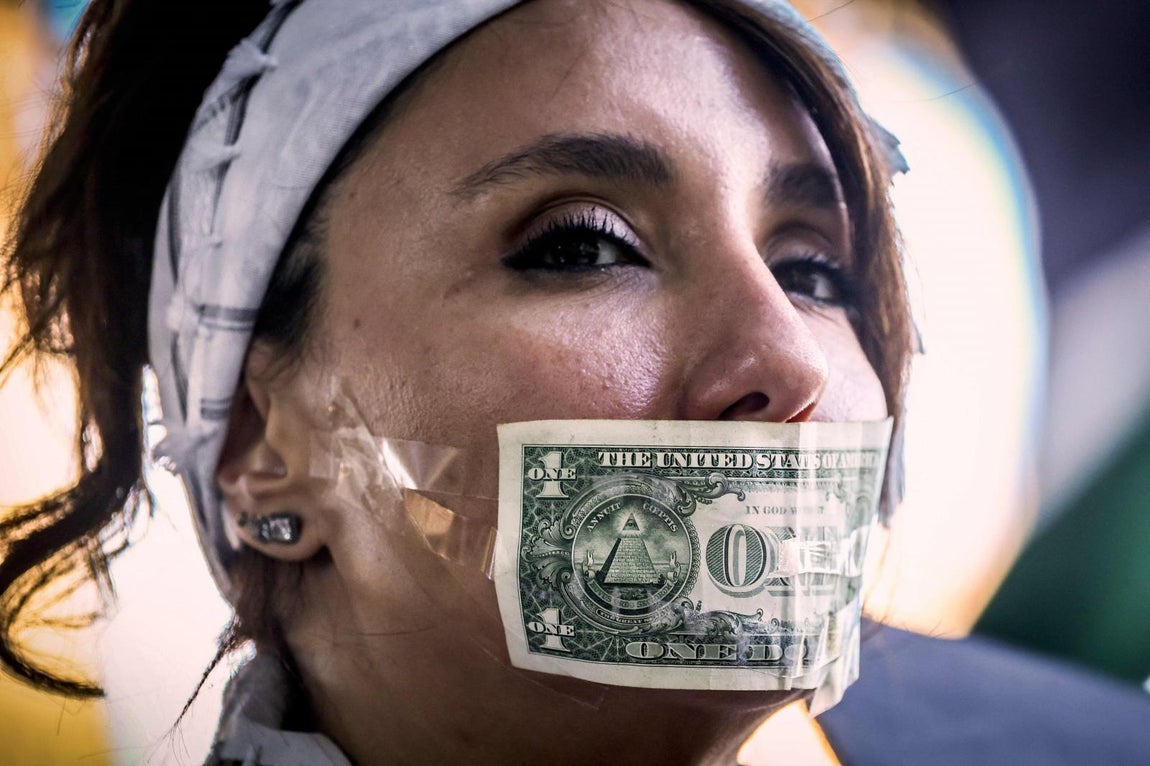 Una manifestante con un billete de dólar estadounidense pegado a la boca participa en una manifestación en apoyo a Irán y los palestinos en Gaza, y contra las acciones de Israel y Estados Unidos.