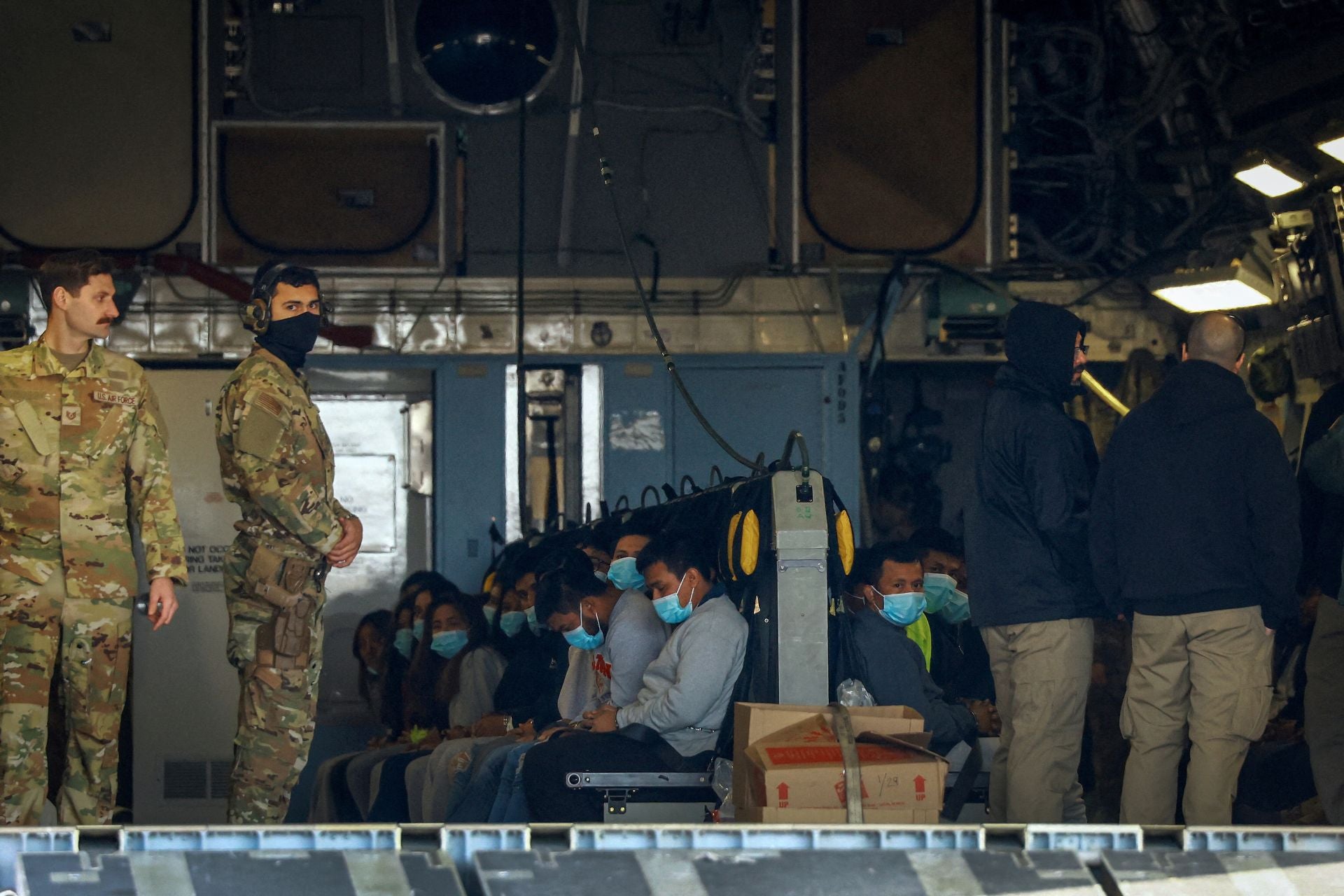 Agentes de la Patrulla Fronteriza trabajan cerca de un avión de la Fuerza Aérea de EE. UU. mientras migrantes expulsados ​​de Estados Unidos se sientan a bordo